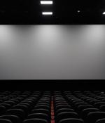 Photo of a movie theater with more than a dozen rows of seats and a large blank screen against the wall.